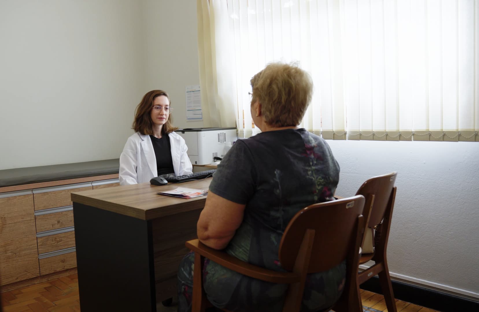Médica geriatra em consulta humanizada com paciente idosa em consultório da Conviva Saúde